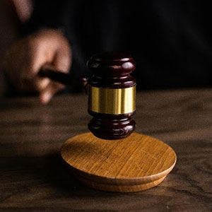 A judge strikes a wooden gavel on a desk in a courtroom. - Law Office of David Nguyen, PC