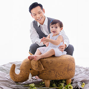 Attorney David Nguyen smiles at a young child sitting on a plush elephant toy - Law Office of David Nguyen, PC.