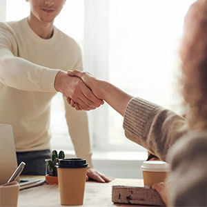 A family member shakes hands with a person, signifying an interview or meeting.
