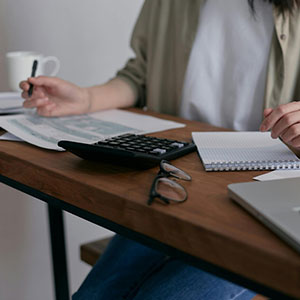 Woman calculating finances with documents and laptop, representing commingled property issues